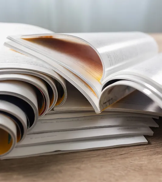 A stack of open magazines or journals on a table.